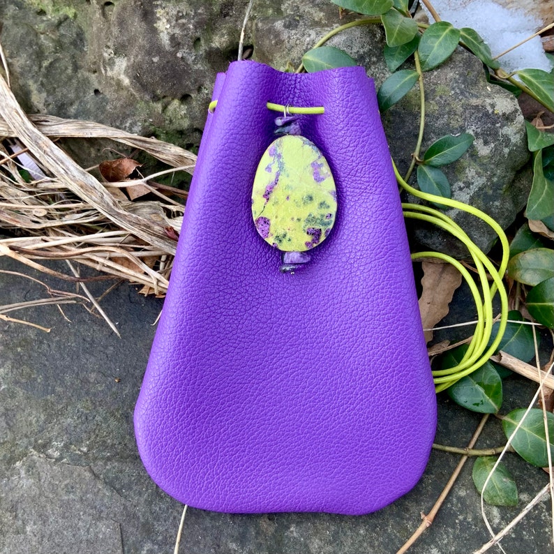 May include: A purple leather pouch with a drawstring closure and a green and yellow stone pendant.