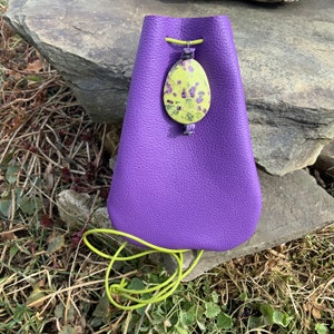 May include: A purple leather pouch with a green drawstring and a green and yellow patterned stone pendant.