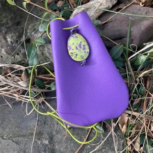 May include: A purple leather pouch with a green drawstring and a green and purple stone pendant.