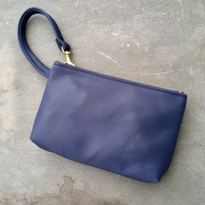 May include: A small, dark blue leather clutch with a gold zipper and a top handle.