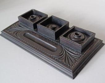 Pode incluir: Um tinteiro de madeira preto com três tinteiros e um porta-canetas. Os tinteiros têm tampas e são decorados com um design entalhado.