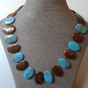 May include: A necklace made of oval-shaped turquoise and brown beads. The beads are arranged in an alternating pattern.