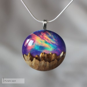 Round pendant handmade with purple lab-created opal, wood and resin. Opals iridescent colors shift from purple to pink, blue, teal, and more, and the wood texture gives the impression of a mountain peaks.