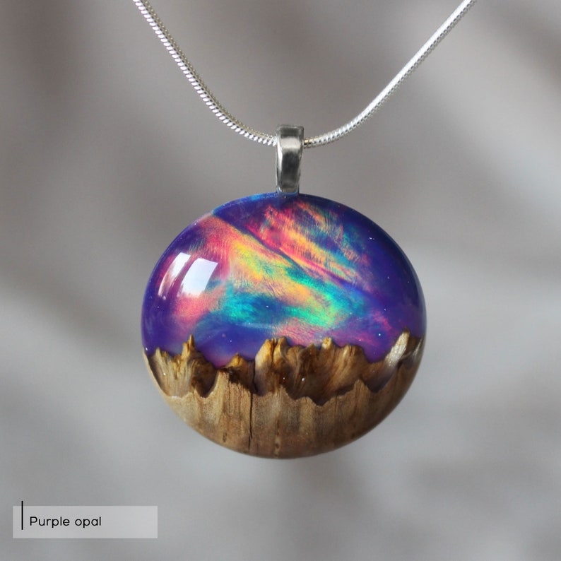 Round pendant handmade with purple lab-created opal, wood and resin. Opals iridescent colors shift from purple to pink, blue, teal, and more, and the wood texture gives the impression of a mountain peaks.