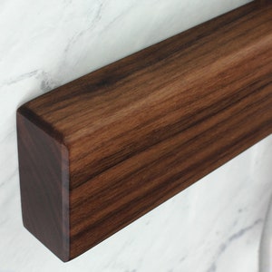 May include: A close-up of a dark brown wooden shelf, showing the grain of the wood.