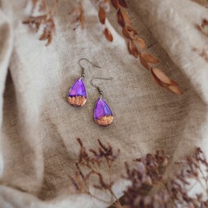 Teardrop earrings handmade with purple lab-created opal, wood and resin. Opals iridescent colors shift from purple to pink, blue, teal, and more, and the wood texture gives the impression of a mountain peaks.