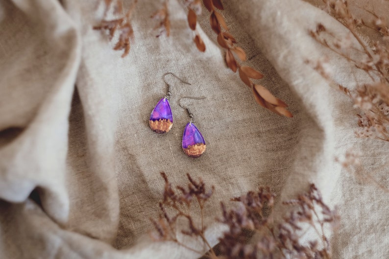 Teardrop earrings handmade with purple lab-created opal, wood and resin. Opals iridescent colors shift from purple to pink, blue, teal, and more, and the wood texture gives the impression of a mountain peaks.