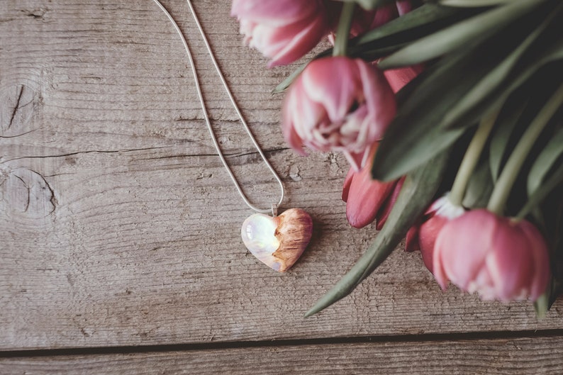 Heart shaped pendant handmade with white lab-created opal, burl wood and resin. Opals iridescent colors shift from white, blue, green, orange, pink & more.