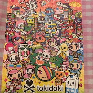May include: A colorful notepad with a Tokidoki logo and a variety of cartoon characters, including a cat, a dog, a bunny, and a unicorn. The notepad is decorated with stars, hearts, and other fun designs.