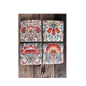 May include: Set of four square coasters featuring a floral pattern. The coasters have a white background with red, orange, blue and green floral designs.