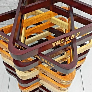 There is a top view of a stack of twelve pool triangles against a white background. There is a various amount of light and dark triangles and brass accented triangles. Each triangle is engraved with a different saying such as The Crocketts Pool Hall