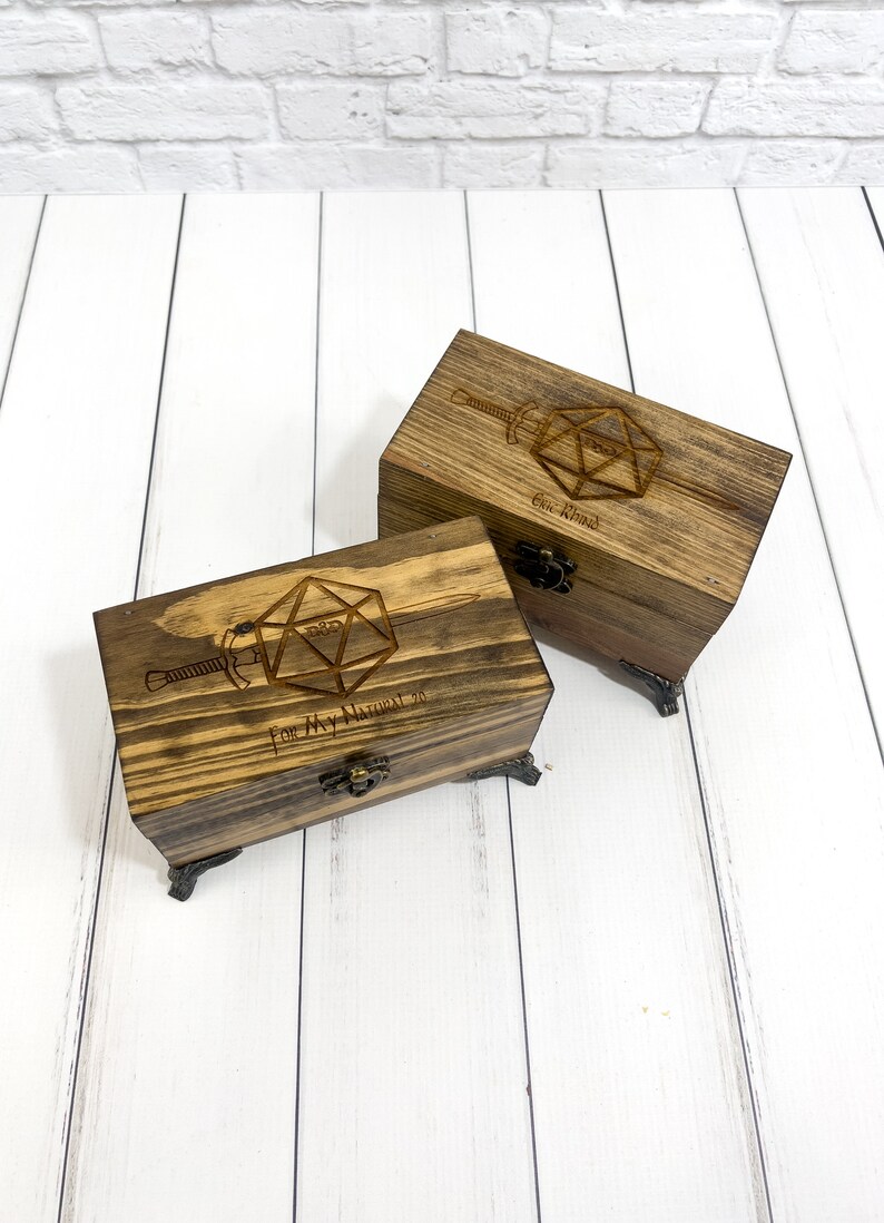 May include: Two wooden boxes with engraved images of a twenty-sided die and a sword. The top box reads "One Kind" and the bottom box reads "For My Natural 20".