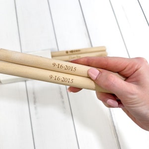 Puede incluir: Dos clavijas de madera con la fecha "9-16-2015" grabada en ellas.