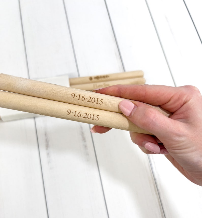 Puede incluir: Dos clavijas de madera con la fecha "9-16-2015" grabada en ellas.