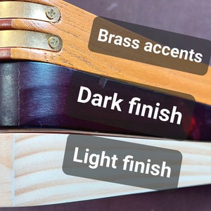 There are three different pool triangles shown a mid stained triangle with brass pieces on the corners labeled Brass accents, a very dark stained triangle labeled Dark finish, finally there is an almost unstained triangle labeled Light finish.