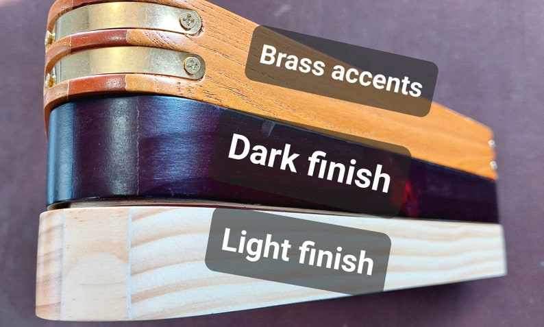 There are three different pool triangles shown a mid stained triangle with brass pieces on the corners labeled Brass accents, a very dark stained triangle labeled Dark finish, finally there is an almost unstained triangle labeled Light finish.