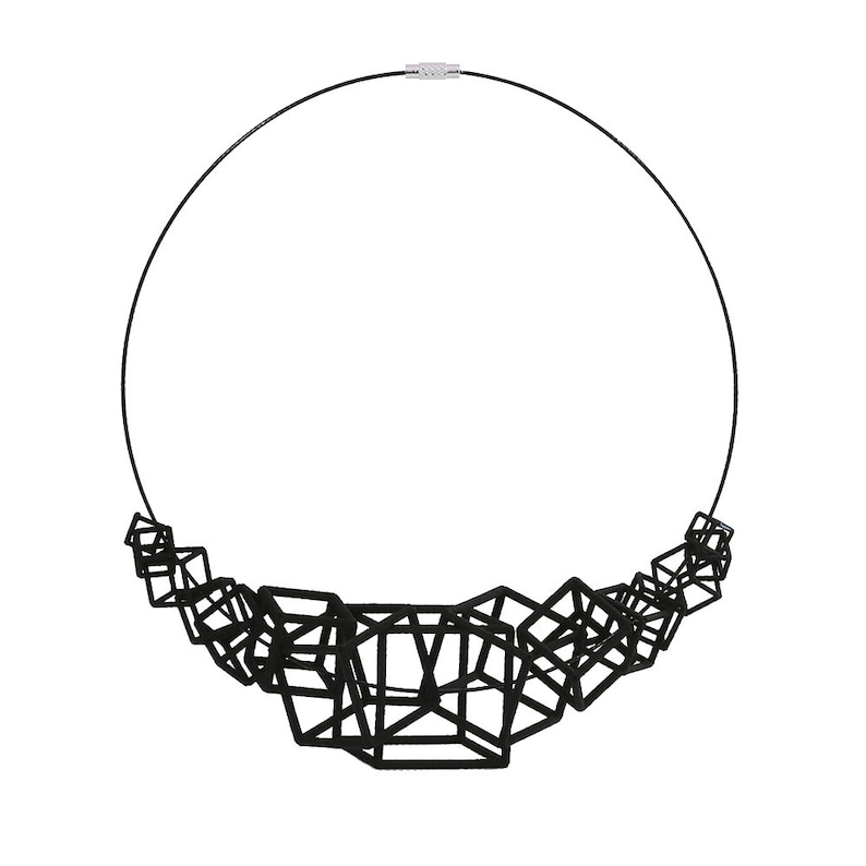 Puede incluir: Un collar negro con un dise&ntilde;o geom&eacute;trico hecho de cubos interconectados. El collar est&aacute; hecho de un metal delgado y negro y tiene un aspecto simple y moderno.