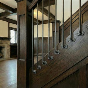 May include: A close-up of a wooden staircase with dark brown wood and metal balusters. The staircase has a classic design with decorative metal accents. The wood grain is visible, and the overall aesthetic is traditional and elegant.