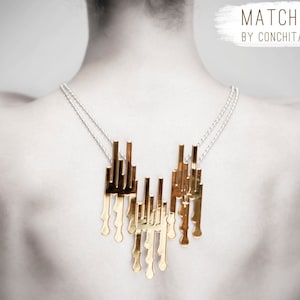 May include: A woman wearing a gold necklace with a geometric design. The necklace is made of multiple thin metal bars that are connected together. The necklace is hanging down the woman's back. The text "MATCH TO BE HAPPY BY CONCHITA PINEDA" is written in white on a gray background.