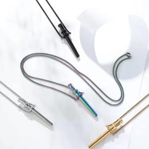 May include: A collection of necklaces featuring a cylindrical pendant design. The pendants are in various colors, including black, silver, gold, and iridescent. Each pendant hangs from a delicate chain, creating a modern and stylish accessory.