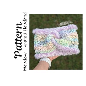 May include: A pastel rainbow colored crochet headband with a purple faux fur trim. The headband is held in a hand.