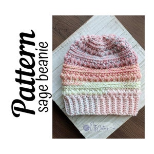 May include: A crocheted beanie hat in shades of pink, white, and gray. The hat has a textured stitch pattern and a folded brim.