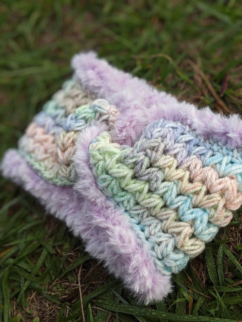 May include: A crocheted headband with a rainbow ombre pattern and a soft, fluffy purple trim.
