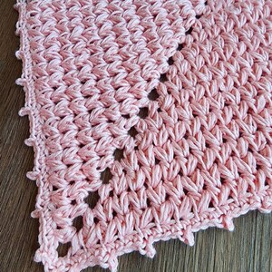 K&ouml;nnte beinhalten: Eine rosa geh&auml;kelte Deckchen mit einem gewellten Rand. Die Deckchen ist mit einem zarten Stichmuster gearbeitet und hat eine Spitzenoptik.
