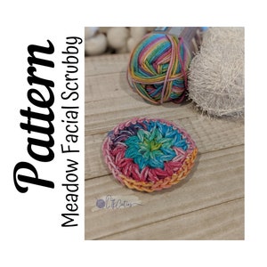 May include: A colorful crochet facial scrubby with a starburst pattern in shades of pink, blue, green, and yellow. The scrubby is made with a soft yarn and is perfect for gentle exfoliation.