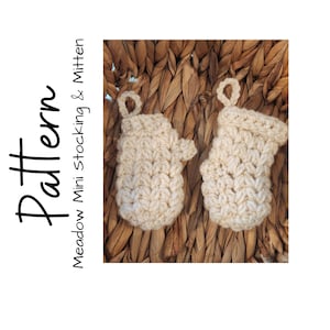 May include: Two cream-colored, crocheted mini mittens and stocking ornaments. The mittens and stocking are made with a textured stitch and have a loop for hanging. The text "Pattern Meadow Mini Stocking & Mitten" is on the left side.