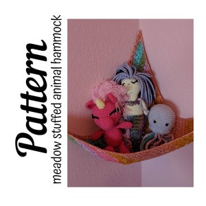 Puede incluir: Una hamaca de crochet con un unicornio rosa, una sirena y un pulpo de peluche dentro. La hamaca está colgada en una esquina de una habitación con paredes rosas.