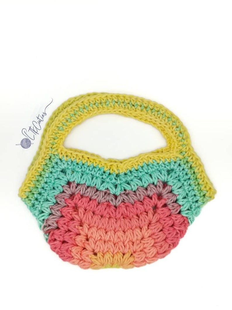 May include: A crocheted rainbow tote bag with a yellow handle. The bag is made with a variety of colors, including pink, orange, yellow, green, and blue.