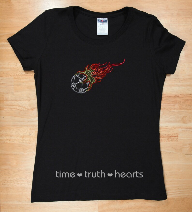 Puede incluir: Camiseta negra con un dise&ntilde;o de bal&oacute;n de f&uacute;tbol de pedrer&iacute;a en llamas. El texto "time truth hearts" est&aacute; impreso en la parte inferior de la camiseta.