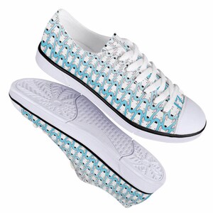 May include: White canvas low-top sneakers with a blue and white patterned design. The pattern features a repeating design of small, stylized figures.