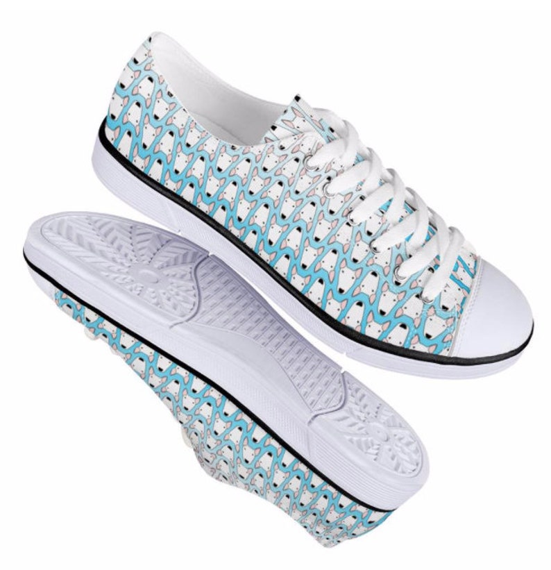 May include: White canvas low-top sneakers with a blue and white patterned design. The pattern features a repeating design of small, stylized figures.