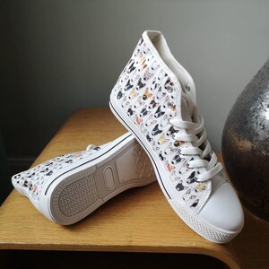 May include: White high-top canvas sneakers with a pattern of colorful bull terrier dog faces.