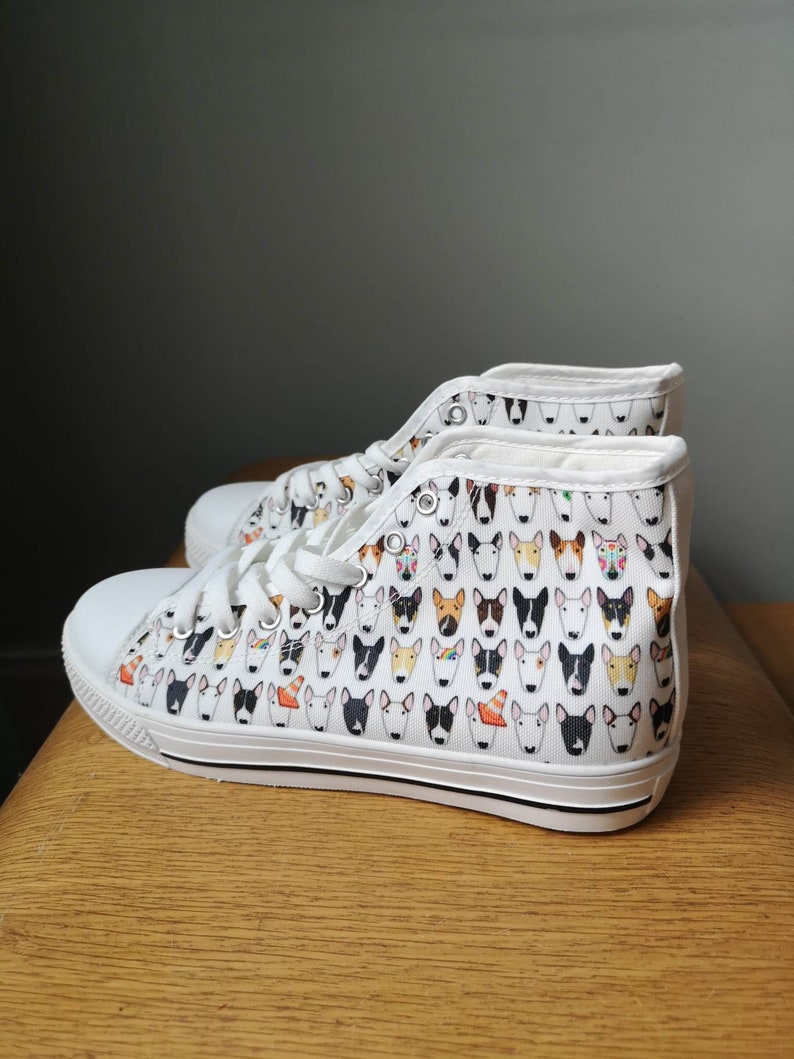 May include: White canvas high-top sneakers with a pattern of colorful bull terrier faces.
