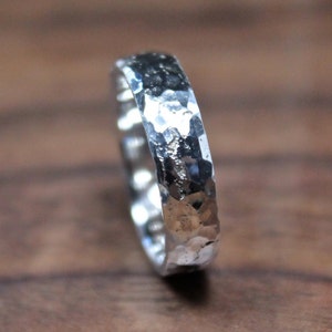 May include: A silver hammered band ring. The ring is made of metal and has a textured surface.