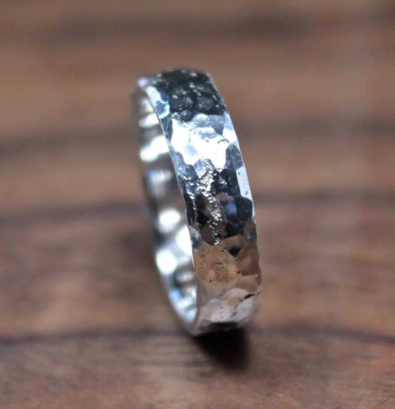 May include: A silver hammered band ring. The ring is made of metal and has a textured surface.