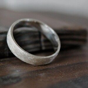 May include: A silver ring with a textured finish. The ring is thick and has a rounded shape.