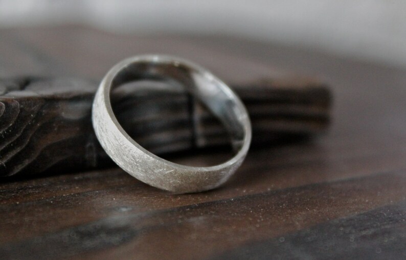 May include: A silver ring with a textured finish. The ring is thick and has a rounded shape.