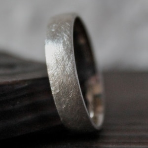 May include: A brushed silver wedding band with a rounded edge.