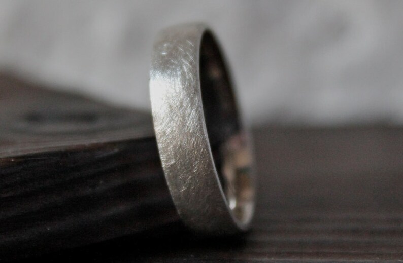 May include: A brushed silver wedding band with a rounded edge.