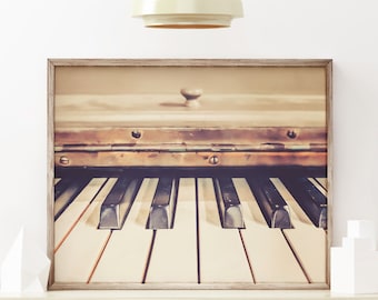 May include: A framed photograph of a vintage piano with ivory keys. The piano is in a rustic setting with a warm, vintage filter applied to the image.