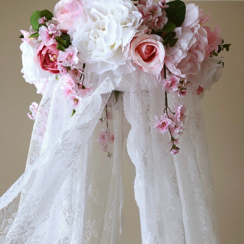 A bed canopy with faux flowers detailing around the top