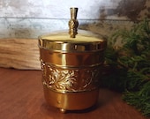 Brass, gold coloured lidded, footed container with thistle embossed design, and thistle knob