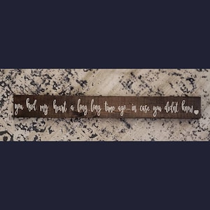 May include: A rustic wooden sign with the text "you had my heart a long long time ago... in case you didnt know." in white lettering. A small white heart is at the end of the text.
