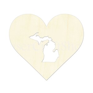 May include: A wooden heart-shaped cutout with the state of Michigan cut out of the center. The heart is a light beige color.