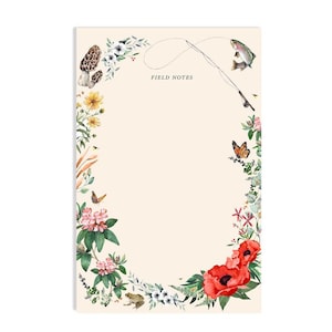 May include: A floral notepad with a cream background and the text "FIELD NOTES" at the top. The floral border features butterflies, a frog, a mushroom, a fish, and a fishing rod.