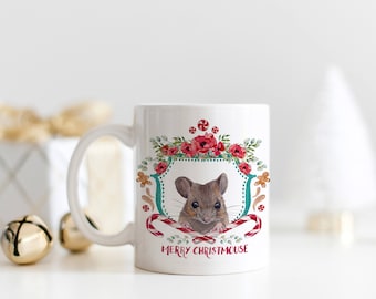 Könnte beinhalten: Weiße Keramiktasse mit einem festlichen Design, das eine Maus zeigt, die aus einem Kranz aus roten Blumen und Zuckerstangen schaut. Der Text "Merry Christmouse" ist auf die Tasse gedruckt.